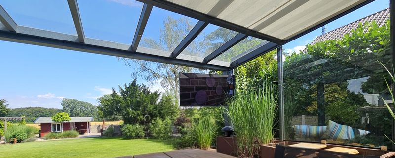 Überdachte Terrasse mit Outdoor-Fernseher und Blick in den Garten