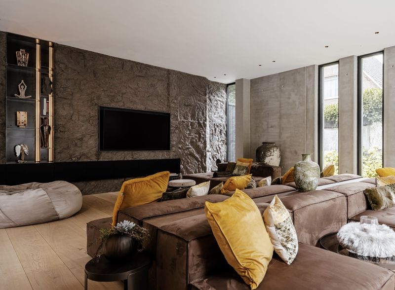 Wohnraum mit Steinwand, eingelassenem Fernseher und beleuchtetem Regal